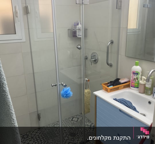 מקלחת זכוכית עם כיור ומראה בחדר אמבטיה